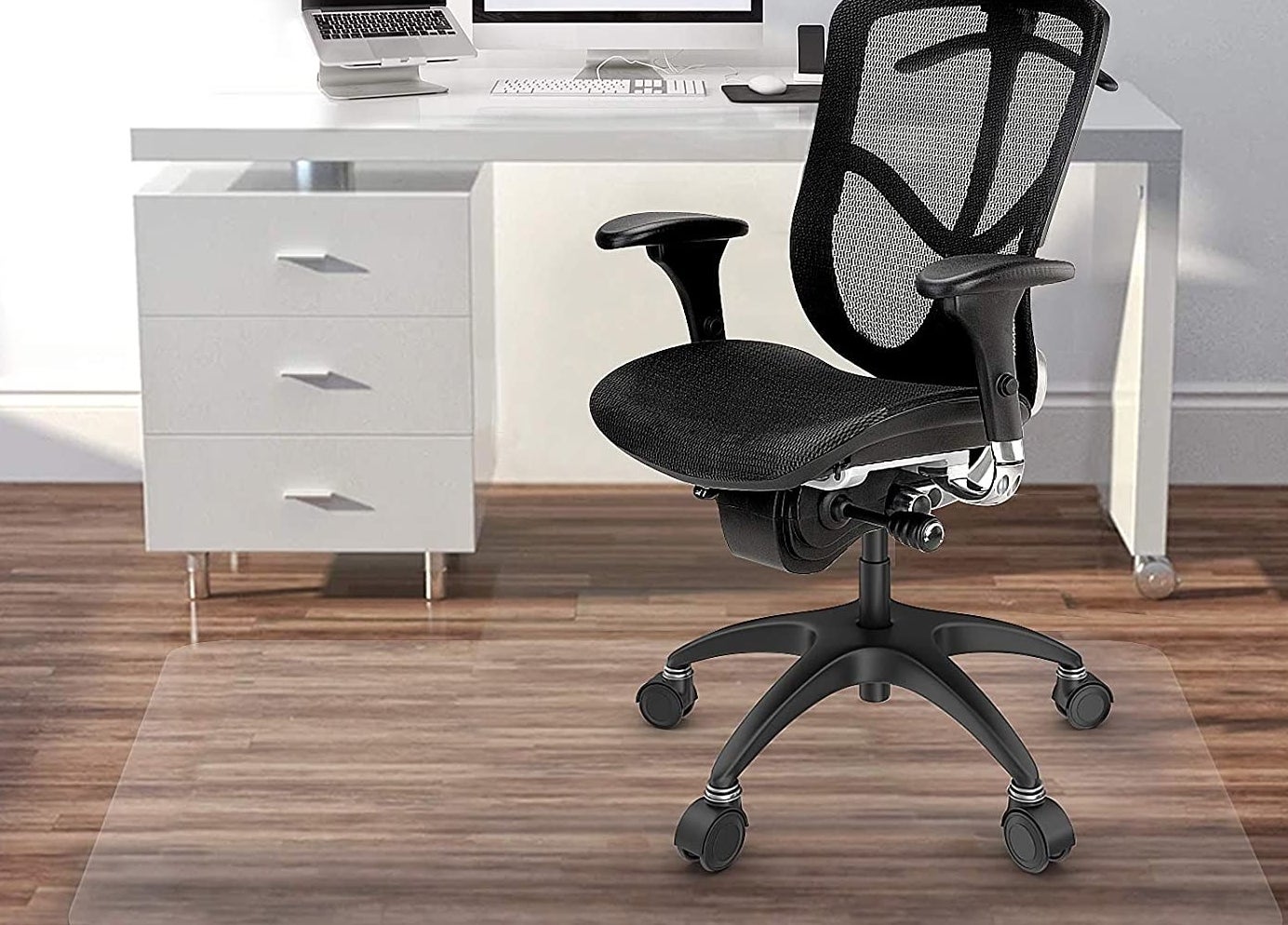 The clear mat in a home office with a rolling office chair on top 