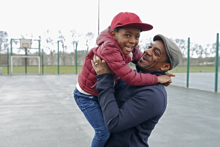 Father holding up young son on basketball court