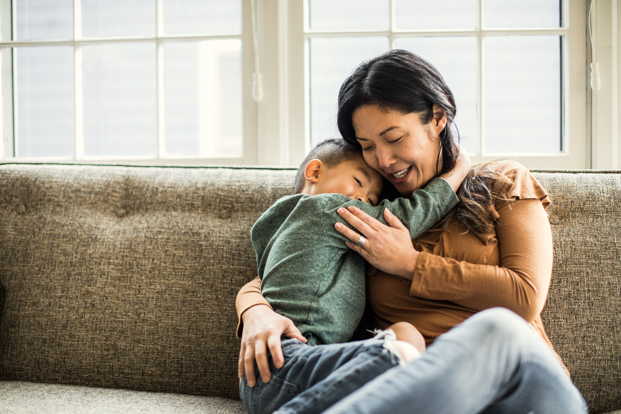 Mother hugging young son on couch