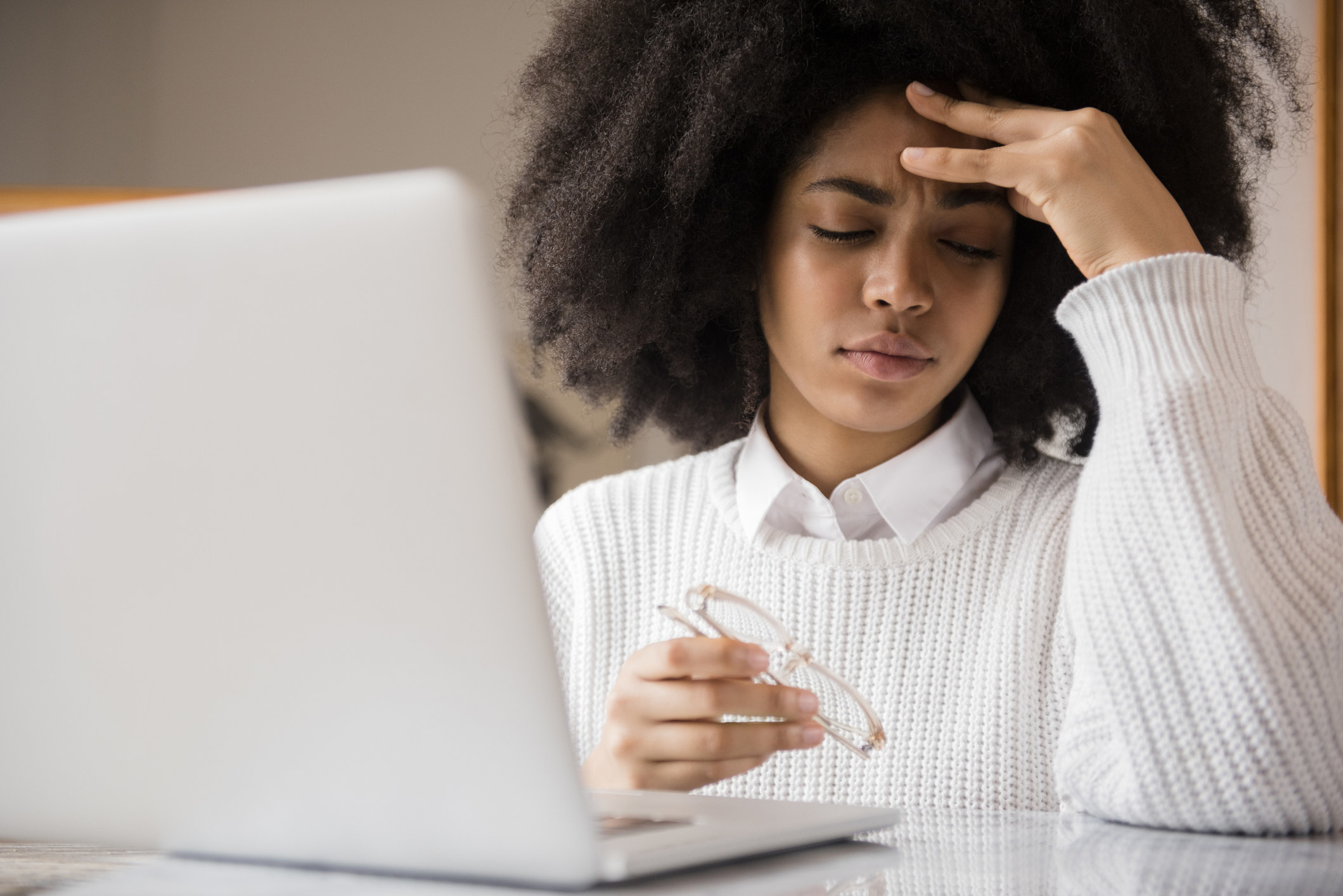 Young woman rubbing forehead while working on laptop