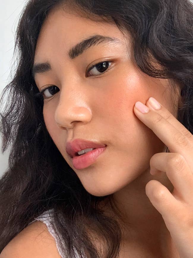 Model applying the blush with two fingers