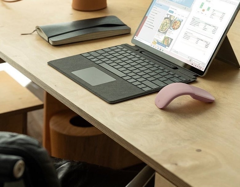 The Microsoft arc mouse beside a laptop