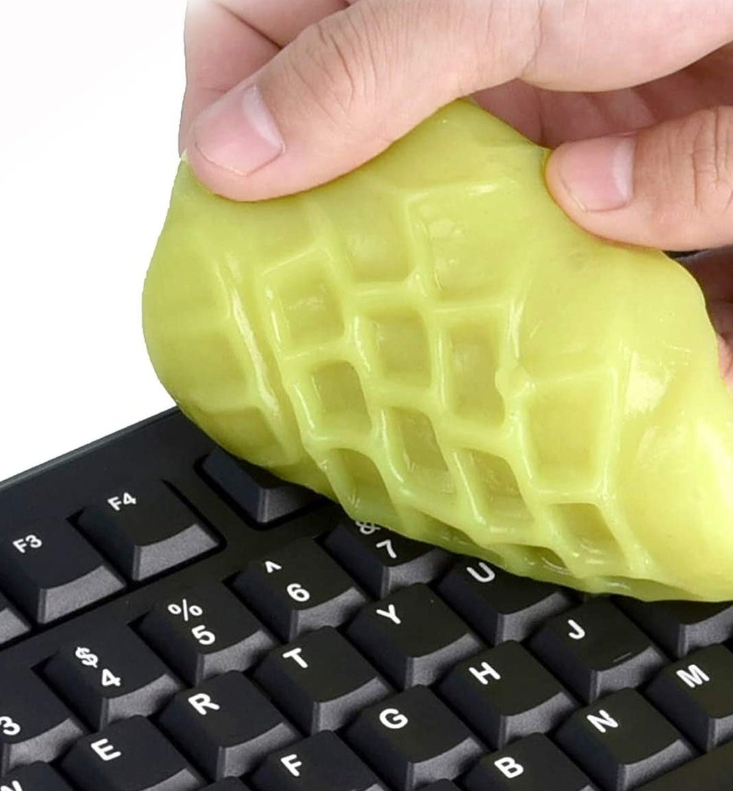 A person cleaning their keyboard with the cleaning putty