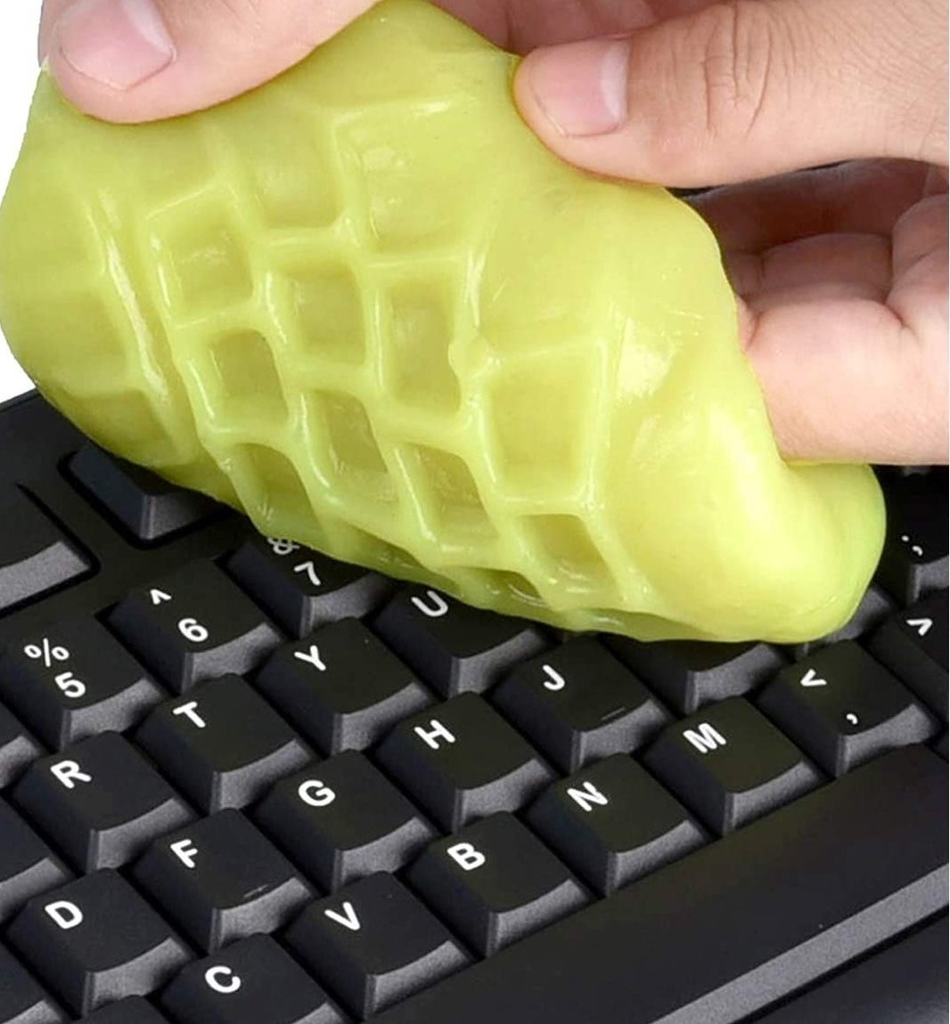 A person cleaning their keyboard with the cleaning putty