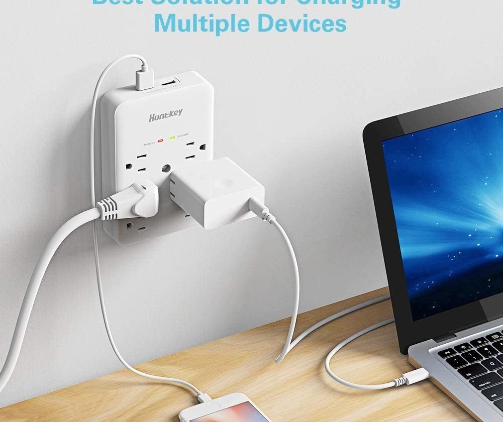 The charging port on a wall above a desk, charging multiple devices simultaneously 