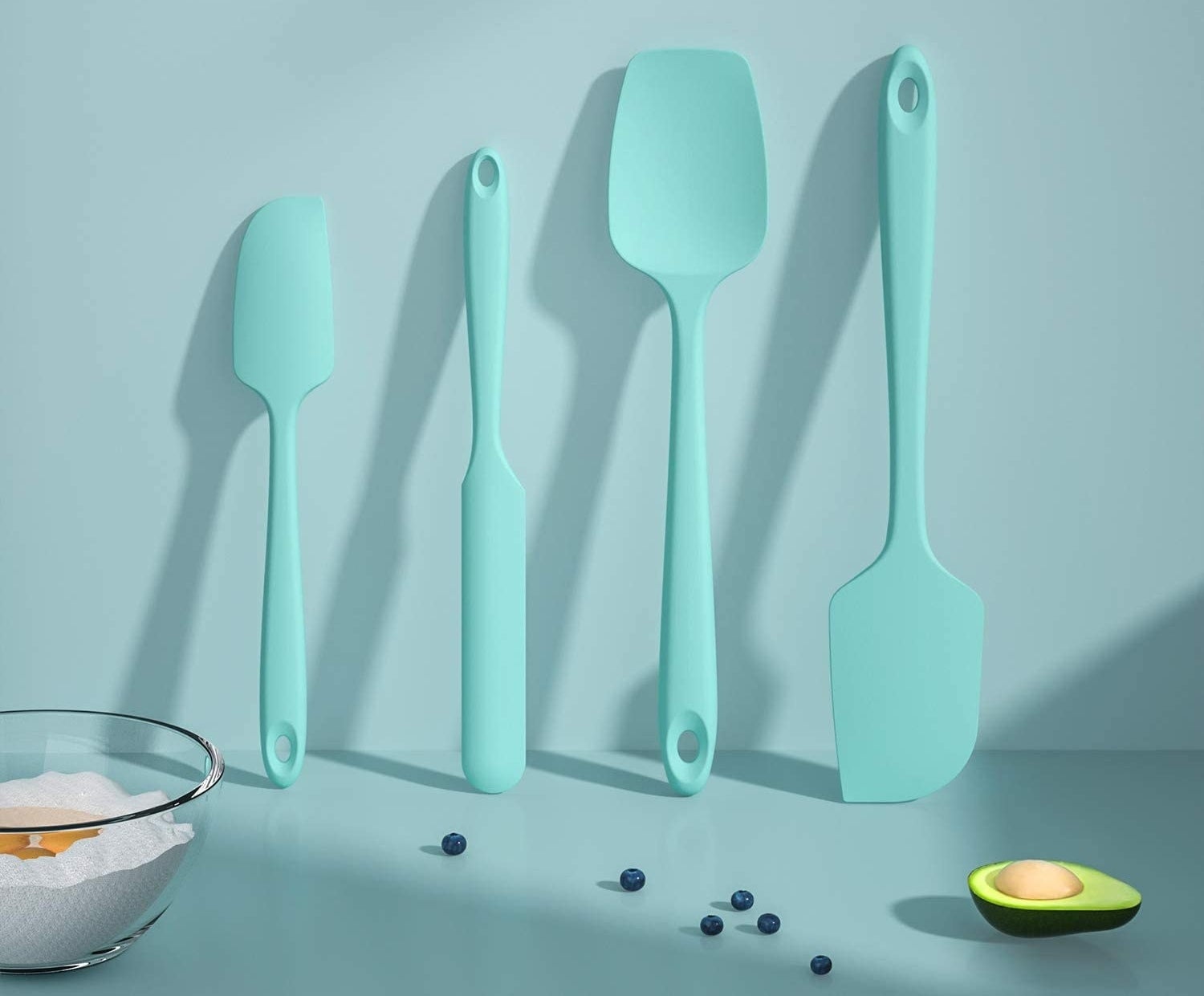 A set of four silicone spatulas leaning against a kitchen wall