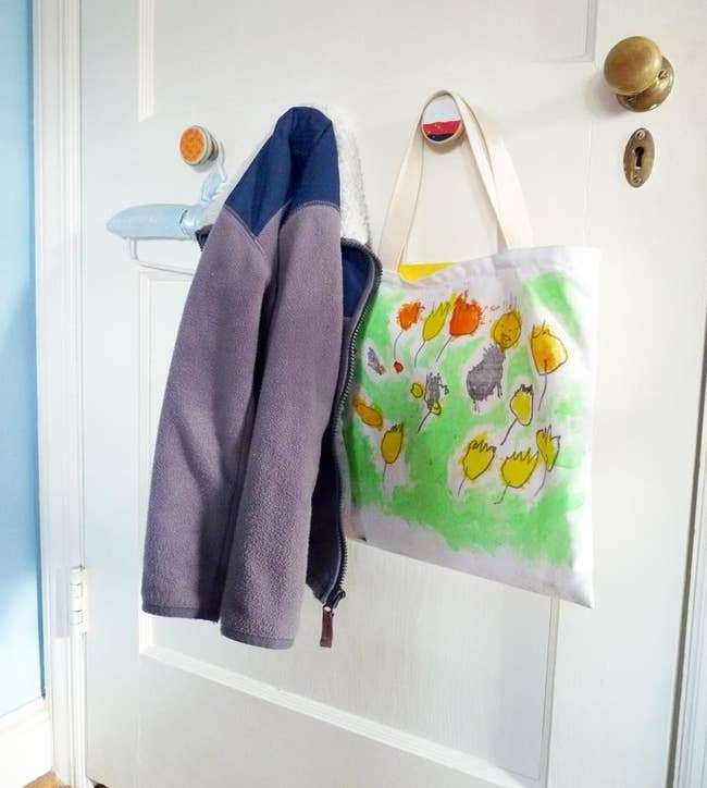 Colorful circle-shaped recycled hooks holding up a zip-up fleece and shopping bag