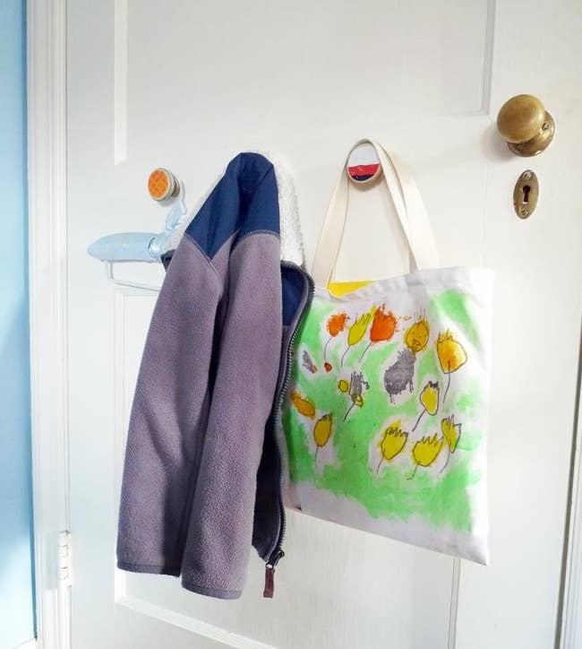 Colorful circle-shaped recycled hooks holding up a zip-up fleece and shopping bag