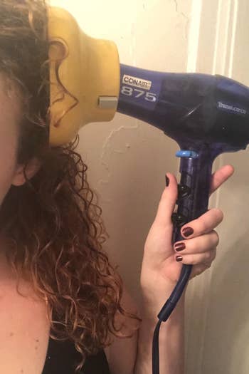 reviewer blow drying their curly hair with the diffuser attachment 