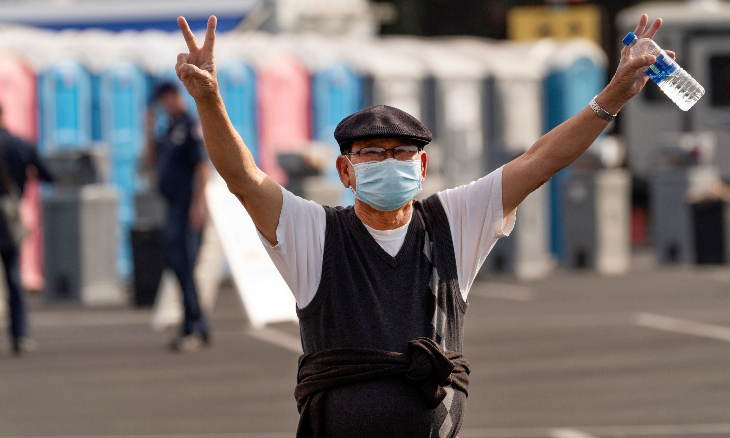 a newly vaccinated man throws peace signs in the air gleefully