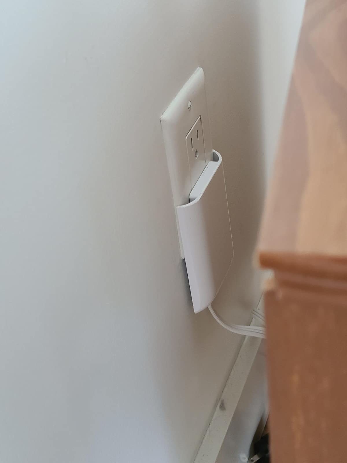 A reviewer&#x27;s photo of the outlet being used behind furniture