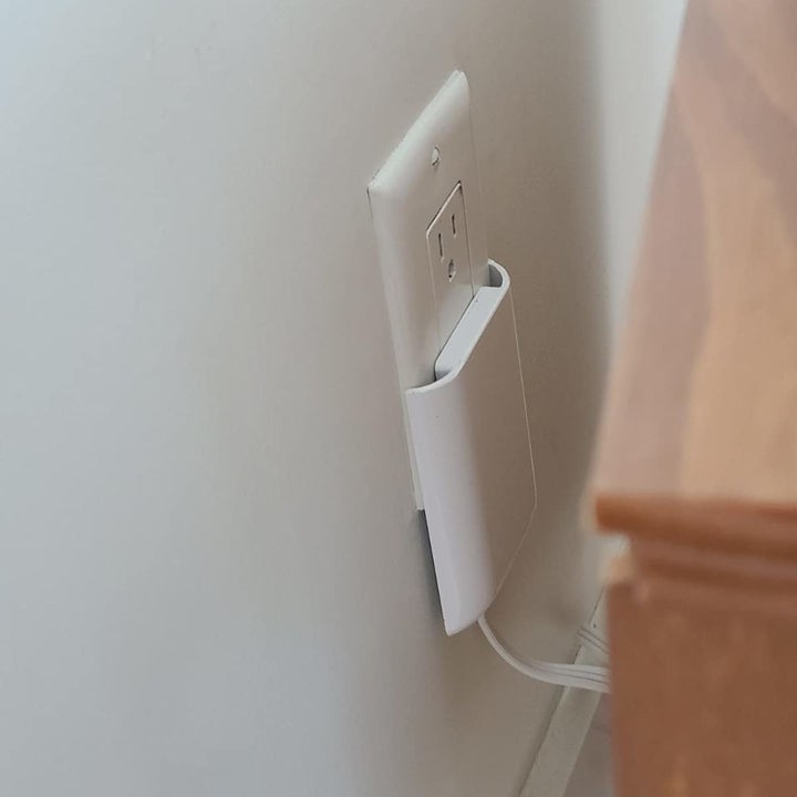 A reviewer's photo of the outlet being used behind furniture