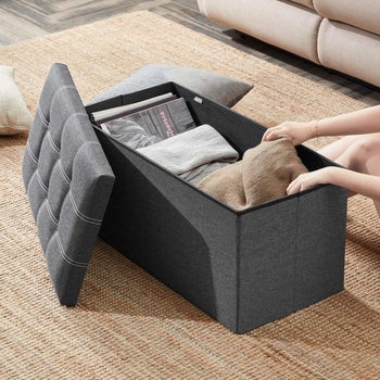 model pulling a blanket out of the storage ottoman 