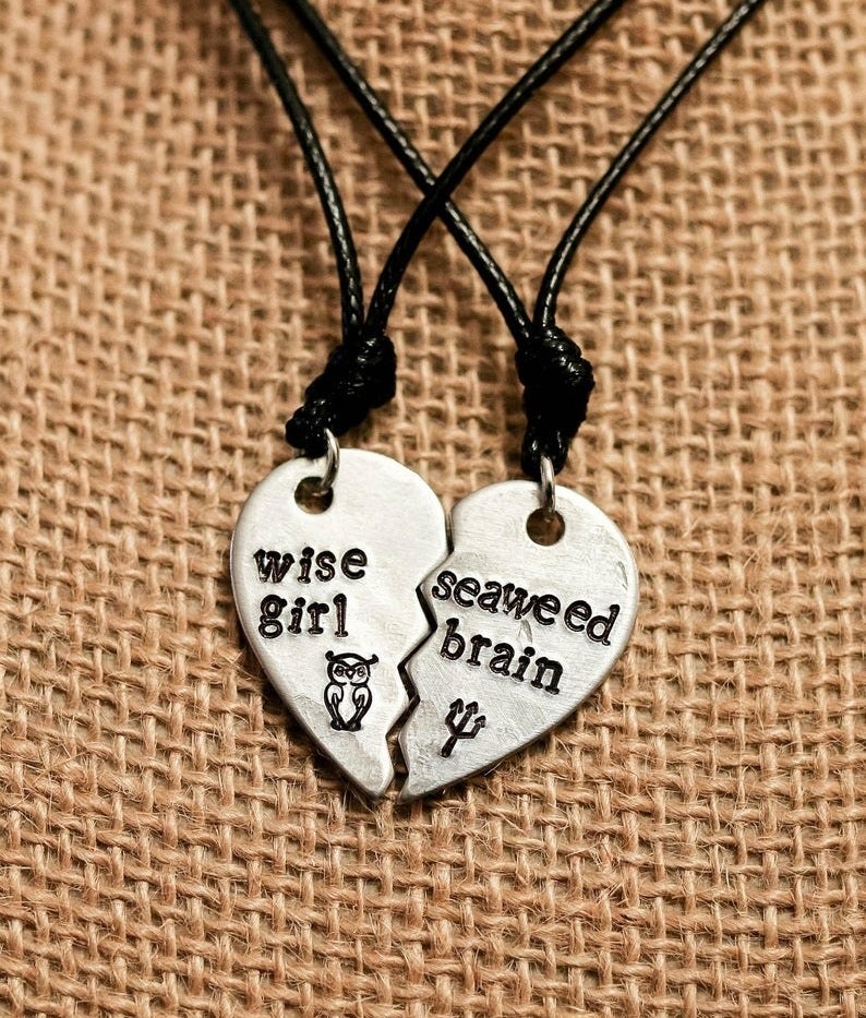 The silver half heart pendants on black cords that fit together. One says &quot;Wise girl&quot; with an owl symbol and the other &quot;Seaweed brain&quot; with a trident