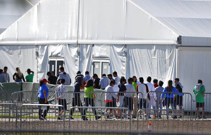 People line up in single file outside a large white tent