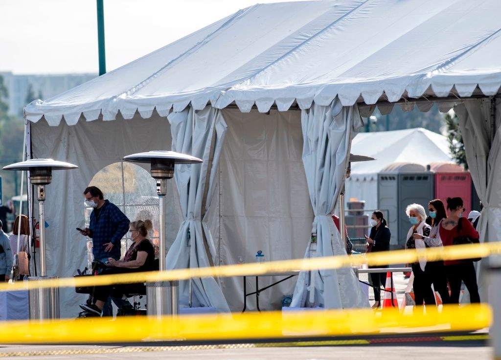 people are seated inside the tents as their vaccines are administered