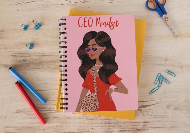 The pink notebook with the words &quot;CEO Mindset&quot; and an illustration of a stylish Black woman on the cover