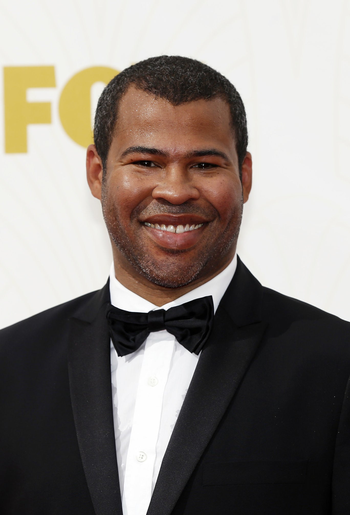 Jordan Peele smiling, wearing a black tux with a bow-tie