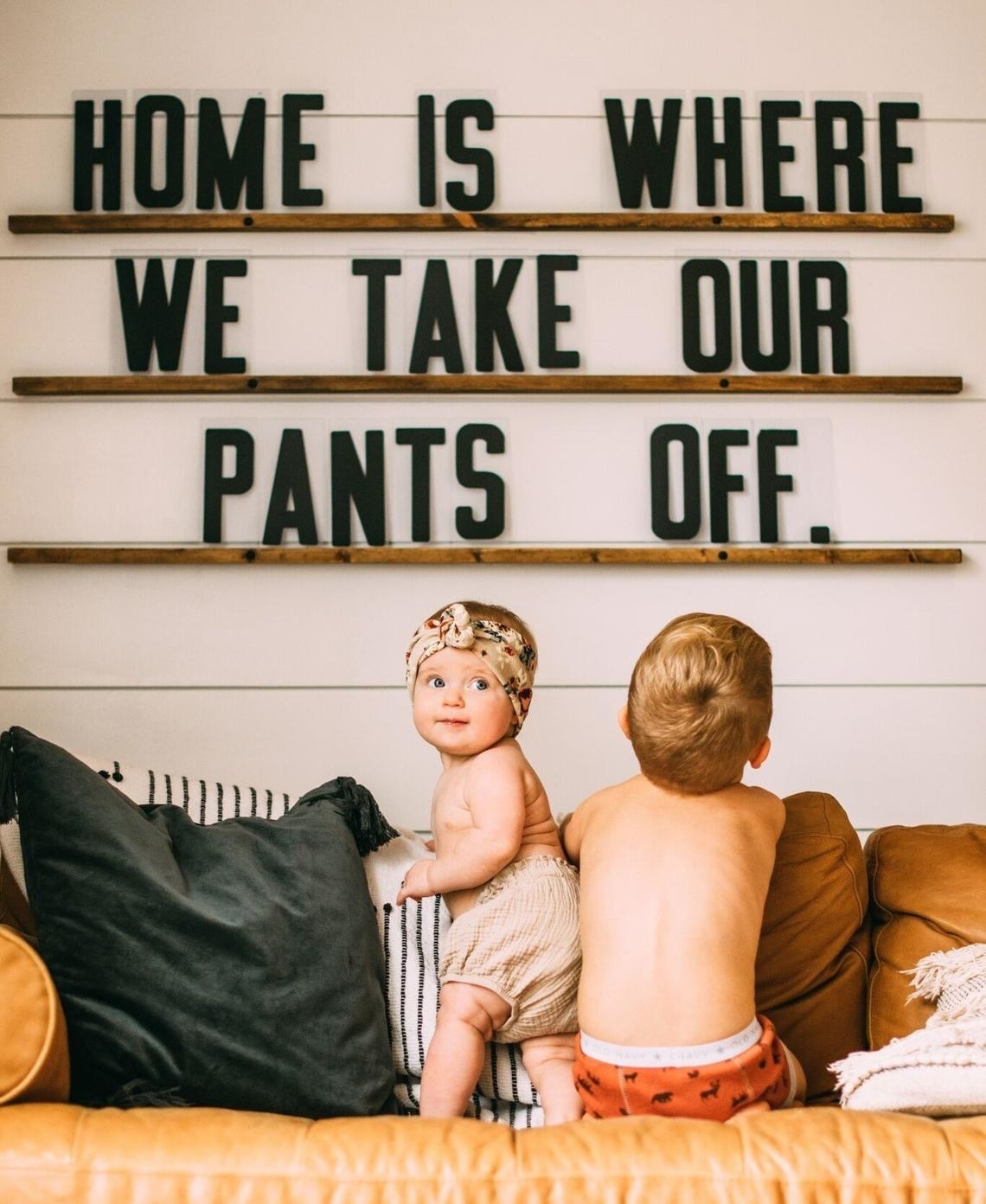 Shallow wooden shelves with words &quot;Home is where we take our pants off&quot; in acrylic lettering 