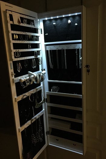reviewer photo showing the jewelry organizer with the door open and LED lights activated