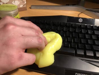 A reviewer photo of a hand pressing the slime against a black keyboard 