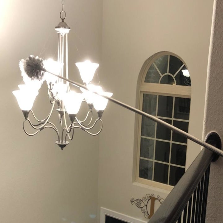 Amazon reviewer using duster to reach lamp hanging in the middle of a hallway