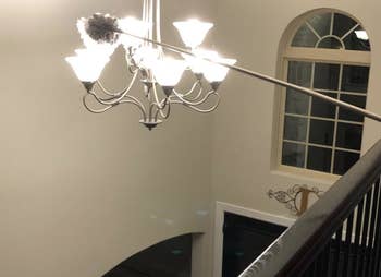 Amazon reviewer using duster to reach lamp hanging in the middle of a hallway