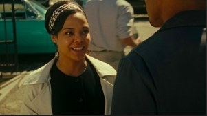 A woman wearing a band-like hair accessory grins at a man.