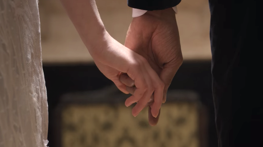 Simon and Daphne holding hands in front of a portrait