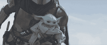 The Mandalorian flying while holding Baby Yoda