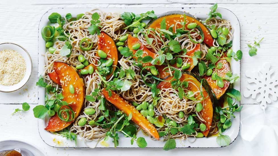 Top down shot of salad with large slices of pumpkin, edamame beans and noodles