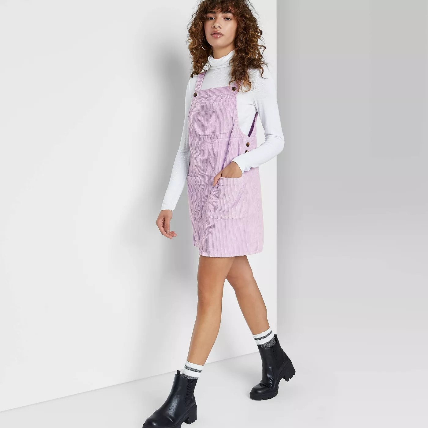 model wears lilac jumper over a white turtleneck and black booties
