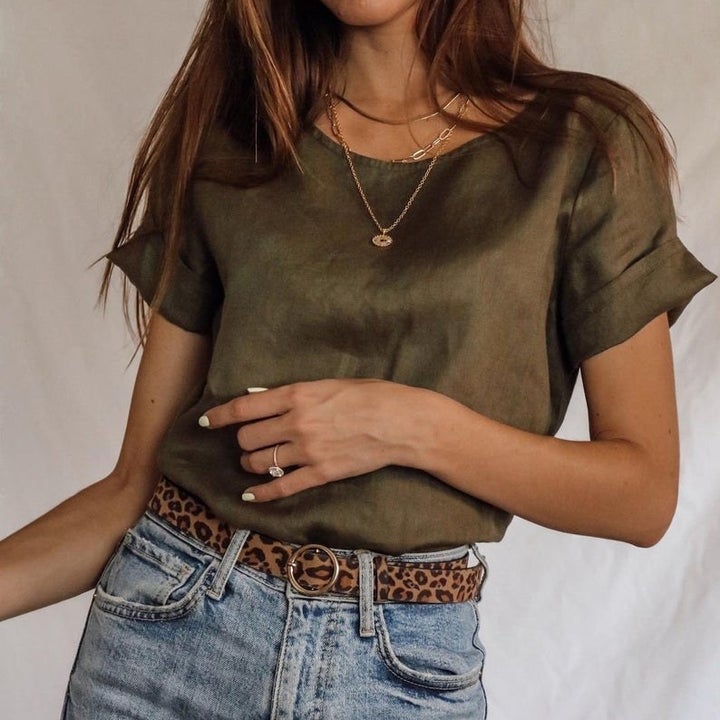 Front view of a model wearing the olive linen shirt tucked into jeans