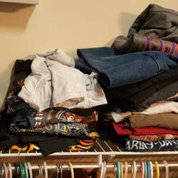 Messy T-shirt piles above a closet rod