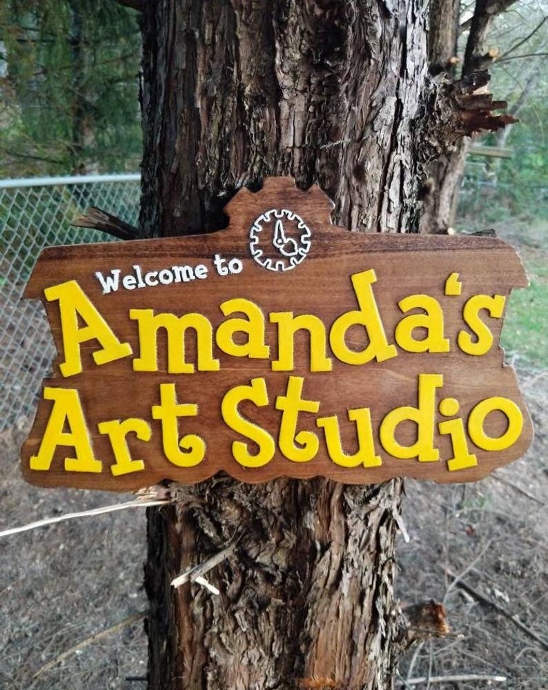 A large wooden sign that looks just like the animal crossing logo but with the words &quot;Welcome to Amanda&#x27;s Art Studio&quot;