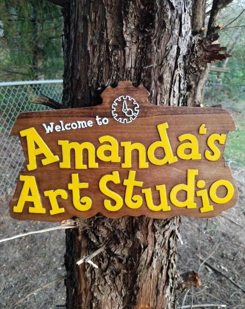 A large wooden sign that looks just like the animal crossing logo but with the words "Welcome to Amanda's Art Studio"