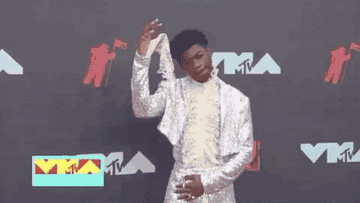 Lil Nas X poses in a sparkly suit on the red carpet at the MTV Video Music Awards