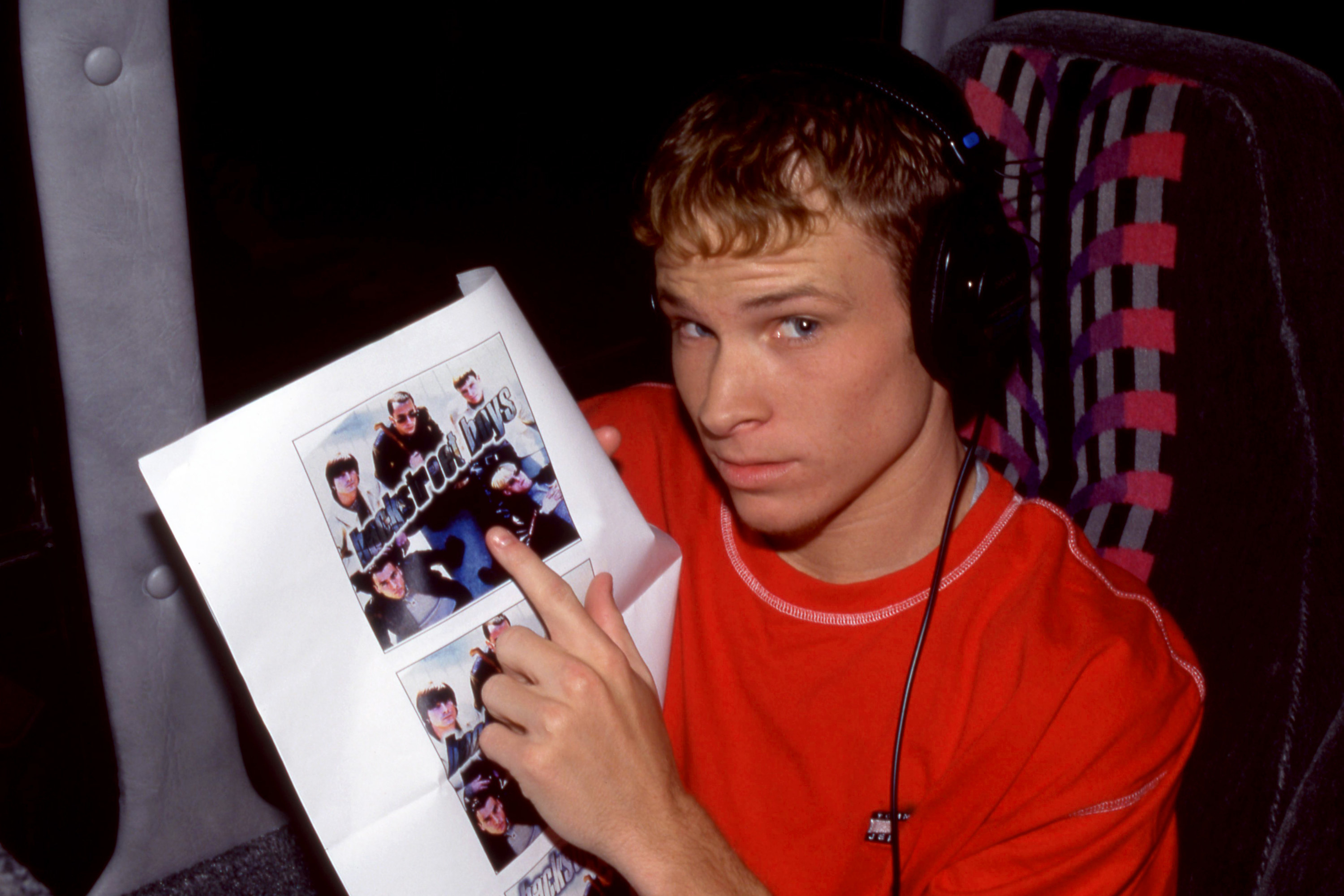 Brian pointing to a promotional photo of the BackStreet Boys