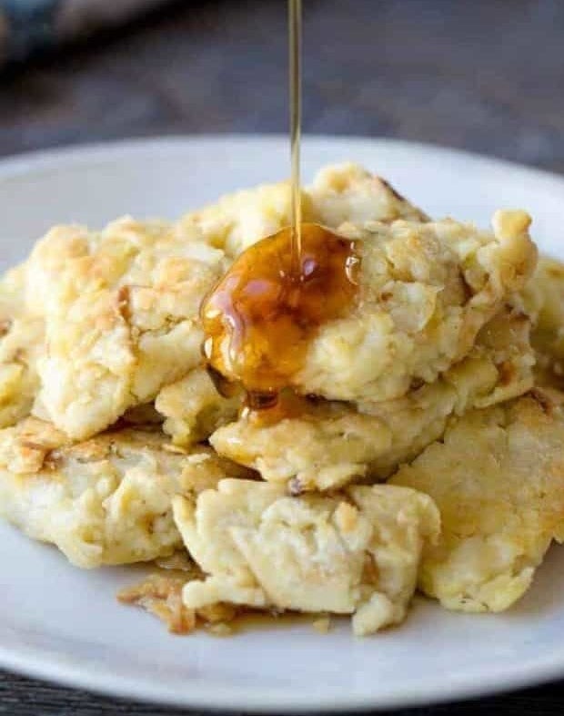 Matzo brei on a plate being drizzled with maple syrup.