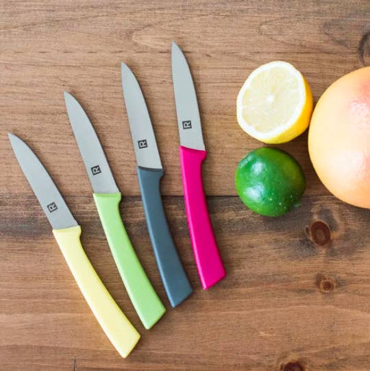 A set of four paring knives with colourful handles on a wooden counter