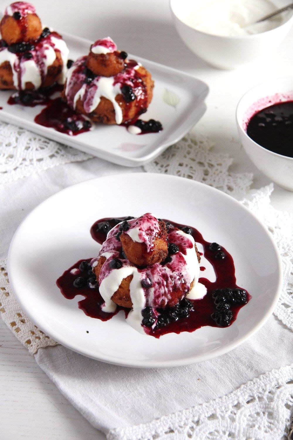 Romanian cheese doughnuts topped with fruit jam and whipped cream.