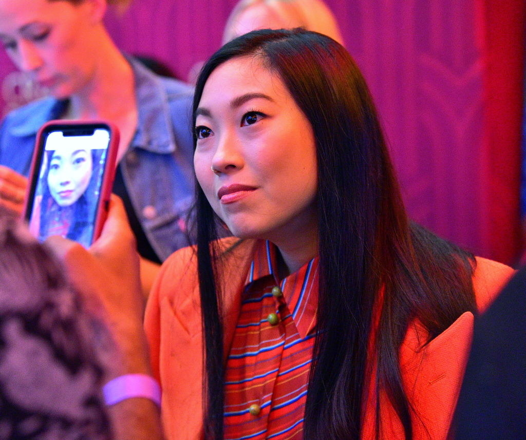 A fan taking a photo of Awkwafina on their cellphone