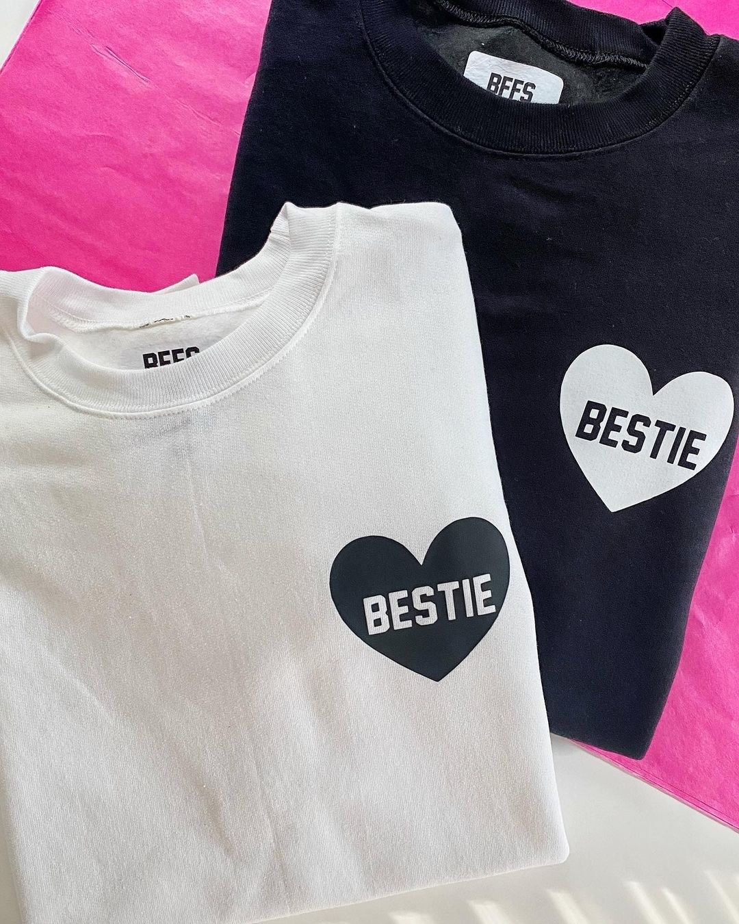 a white sweatshirt with a black heart that says bestie in it and a black one