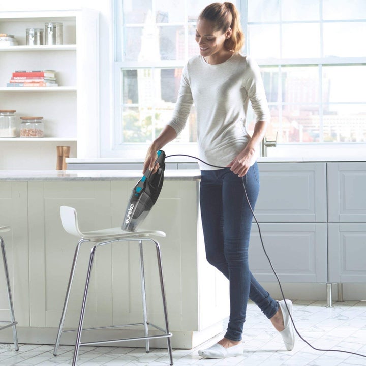 Model using Bissell vacuum in handheld mode to clean a chair