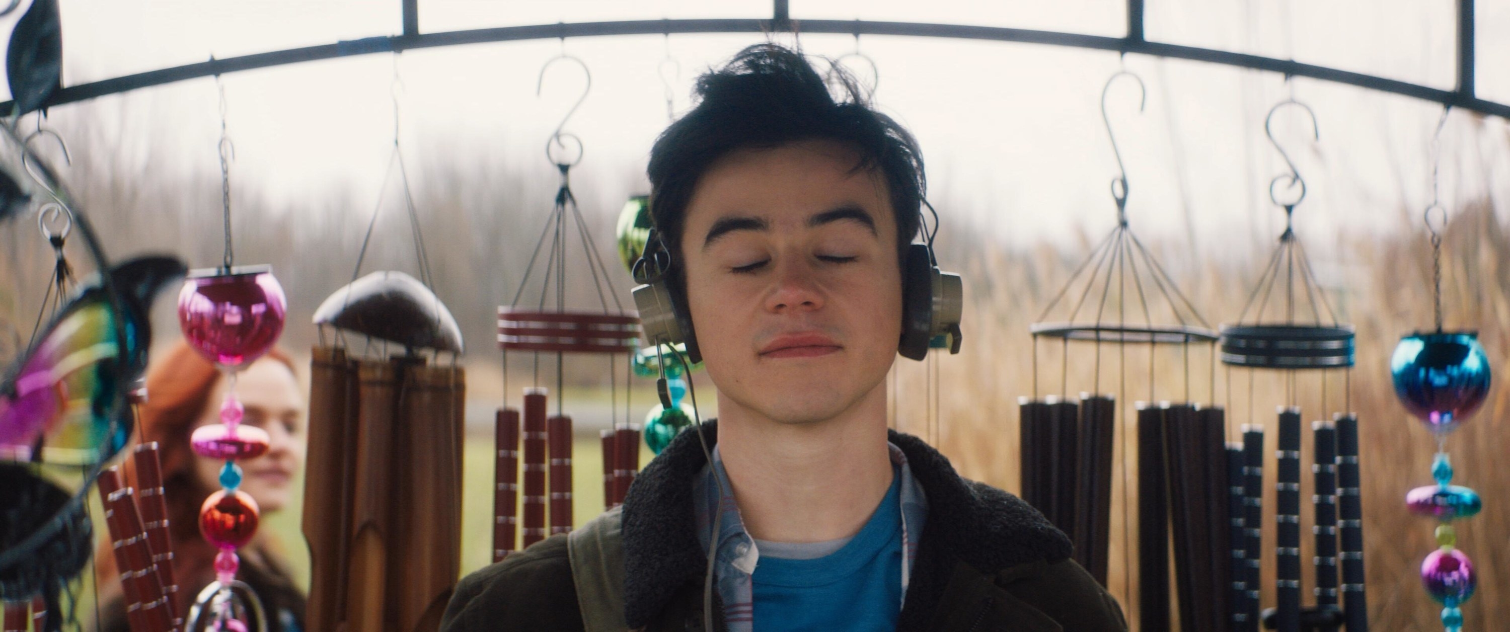 Marcus standing in field surrounded by wind chimes 