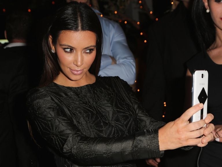 Kim Kardashian taking a selfie in a black outfit