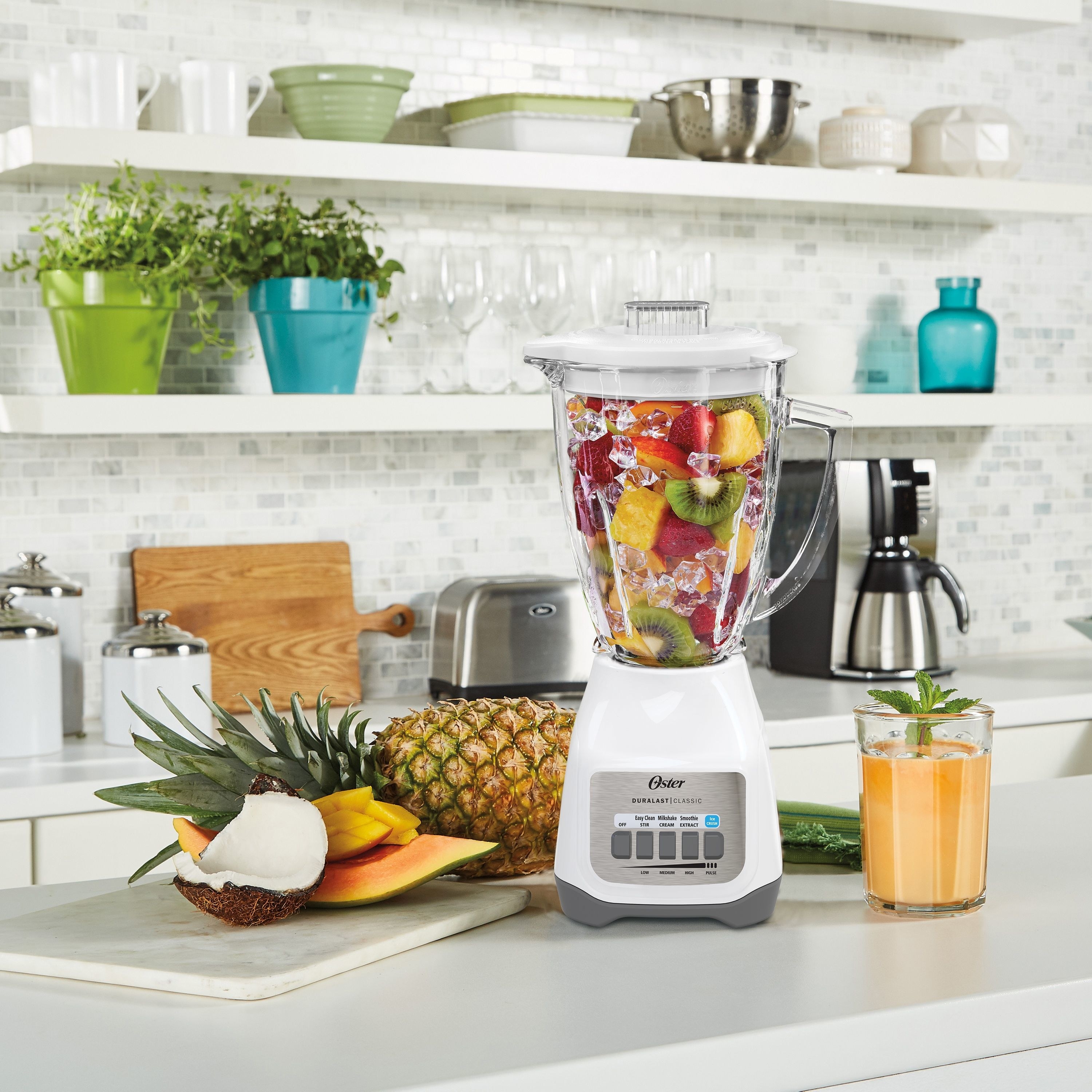 the blender in white with ingredients to make smoothies inside and around it 