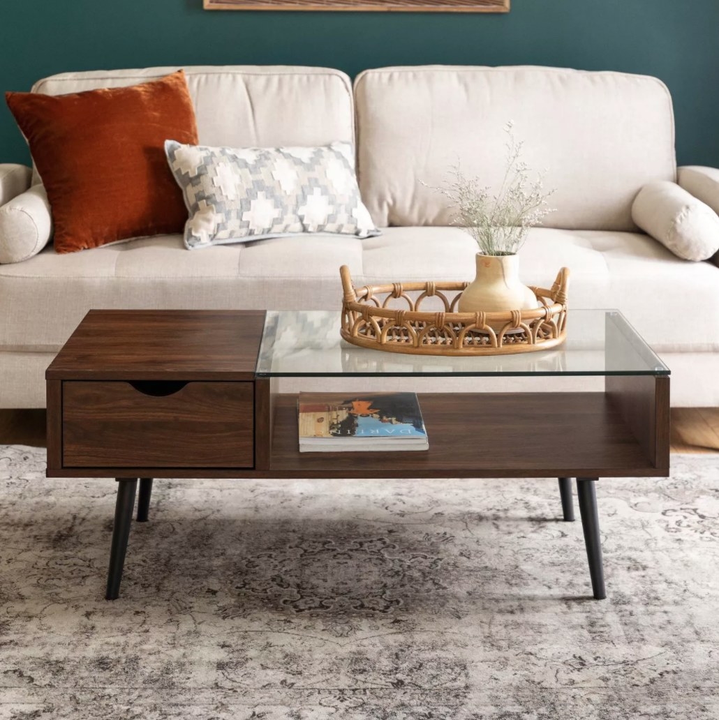 A brown wooden coffee table with a glass top and one drawer