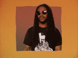 A man with locs and wearing sunglasses hesitantly raises his hand. 