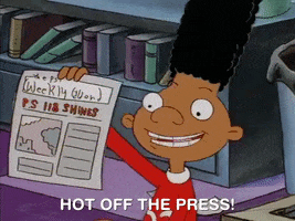 A boy with a very high flat top holds a newspaper. 